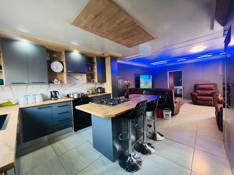 Modern open-plan kitchen and living area featuring contemporary cabinetry, a central island with a gas hob, and stylish recessed ceiling lighting.