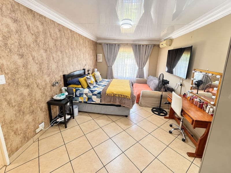 A bedroom featuring tiled flooring, a glossy stretch ceiling, crown molding, and a wall-mounted air conditioning unit.