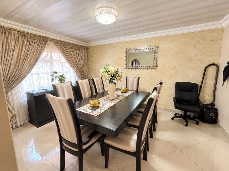 A well-maintained dining room featuring polished tiled flooring, textured wall finishes, and a decorative ceiling light fixture.