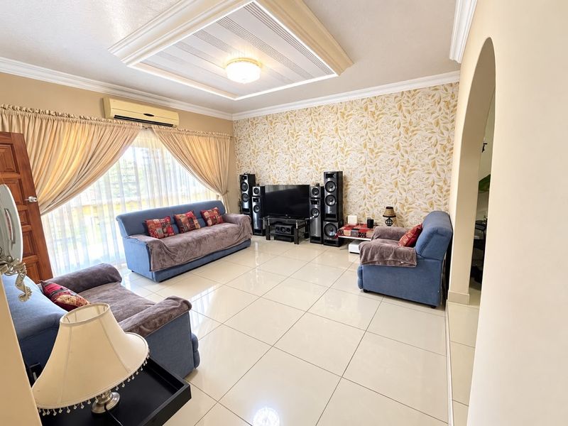 Spacious living room featuring a decorative tray ceiling, tiled flooring, and a feature wallpaper wall, complemented by a wall-mounted air conditioning unit.