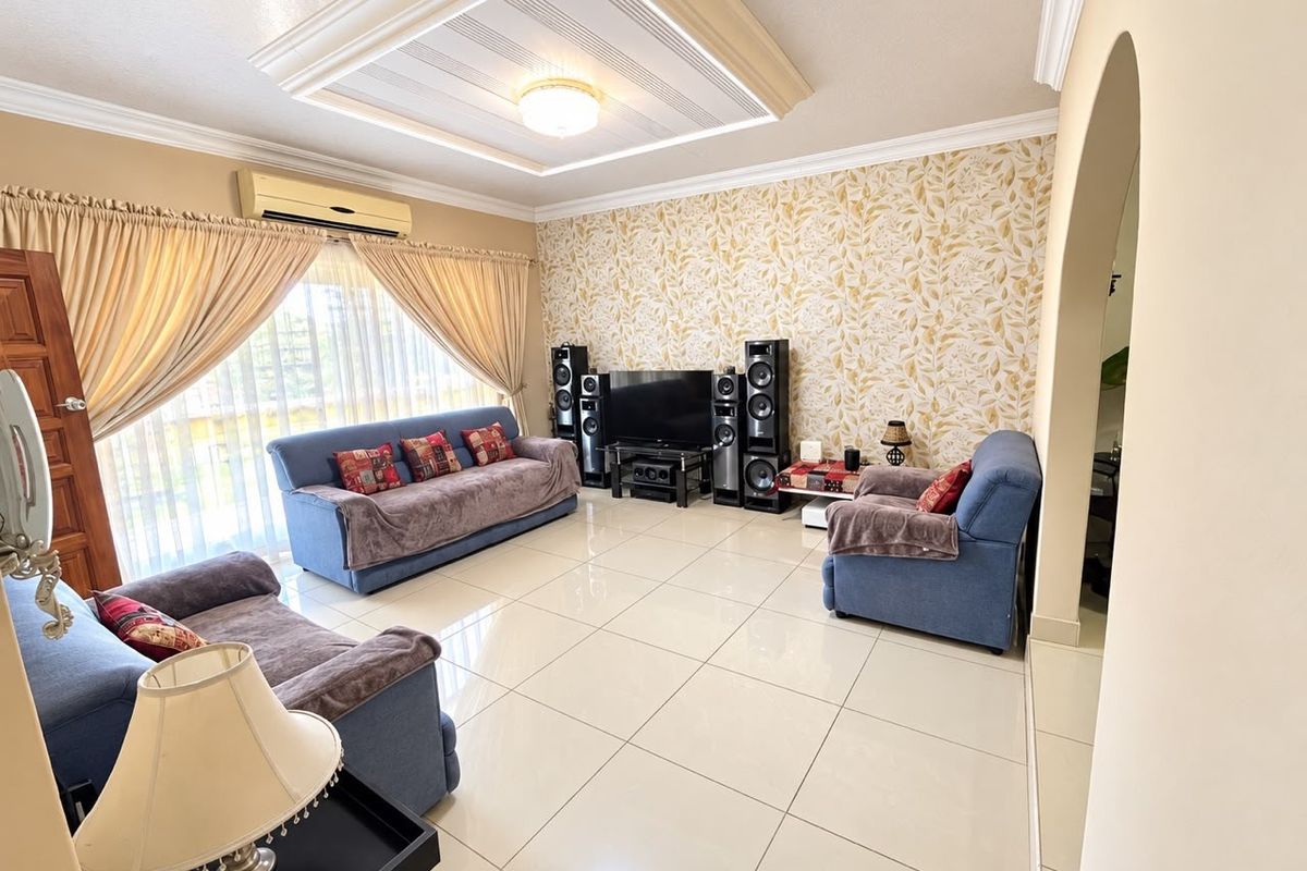 Spacious living room featuring a decorative tray ceiling, tiled flooring, and a feature wallpaper wall, complemented by a wall-mounted air conditioning unit.