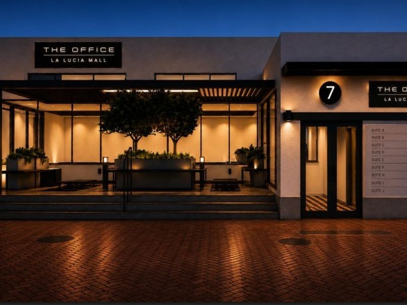 Modern office building entrance at La Lucia Mall featuring professional signage, paved driveway, and integrated exterior lighting.