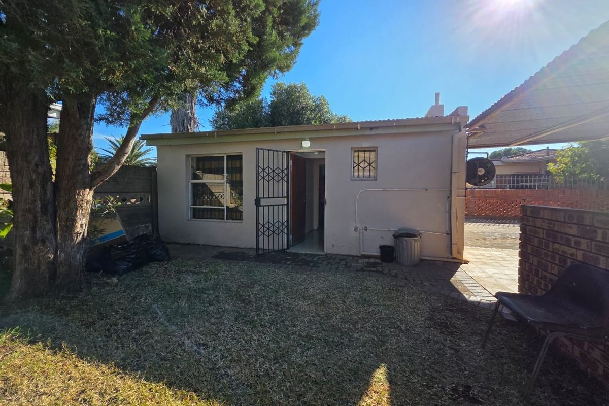 Rear view of the property featuring a paved patio area, security gate, and established garden space.