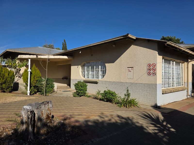 Front exterior view of a single-story house featuring a paved driveway, stucco and brick facade, and a covered entrance area.