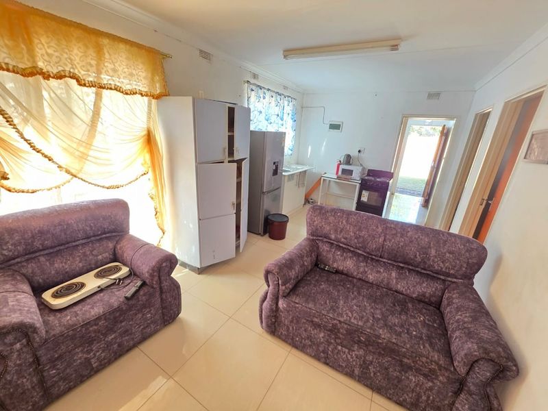 Open plan living and kitchen area featuring tiled flooring, basic cabinetry, and direct access to an exterior doorway.