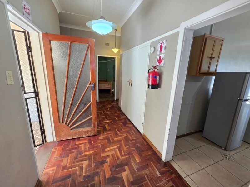 A functional hallway featuring classic parquet flooring, built-in storage cupboards, and a decorative timber door leading to adjacent living spaces.