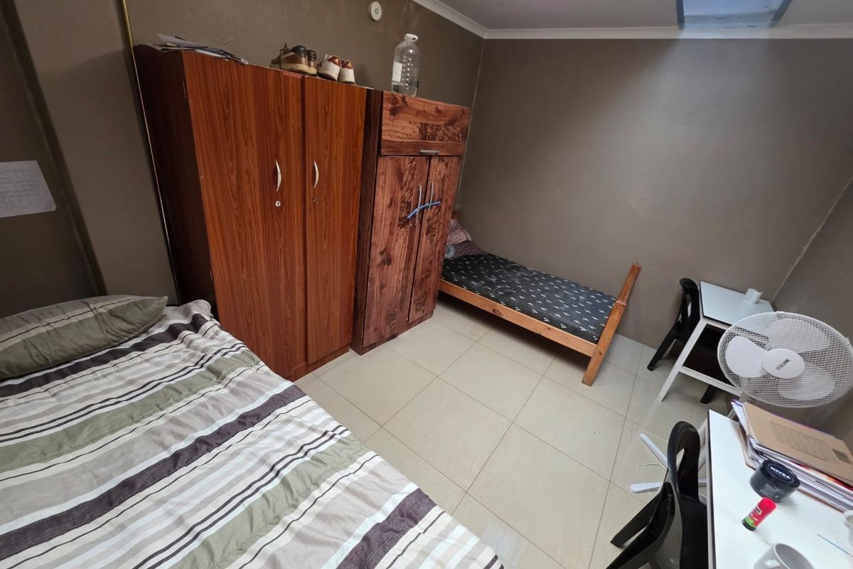 A bedroom featuring tiled flooring and coved ceilings, currently showing signs of wear on the walls requiring maintenance or cosmetic updates.