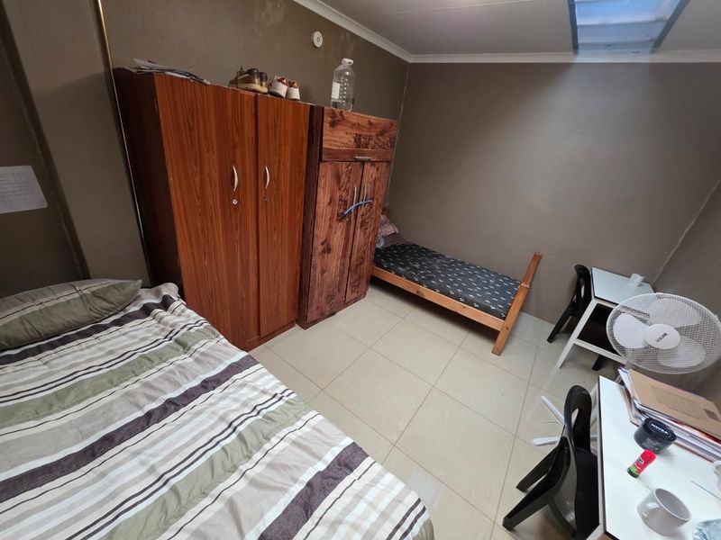 A bedroom featuring tiled flooring and coved ceilings, currently showing signs of wear on the walls requiring maintenance or cosmetic updates.