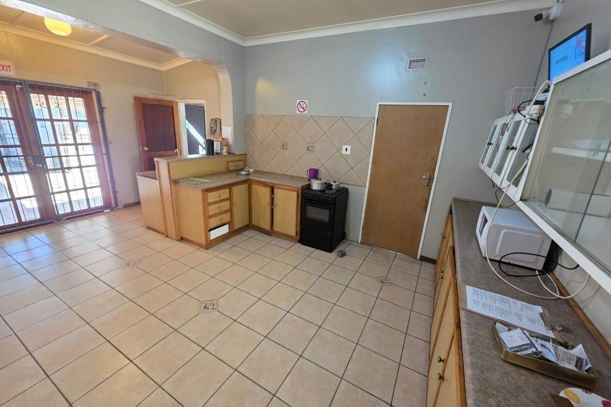 A functional kitchen featuring tiled flooring, built-in cabinetry with laminate countertops, a freestanding stove, and a tiled splashback, with direct access to an exterior door.