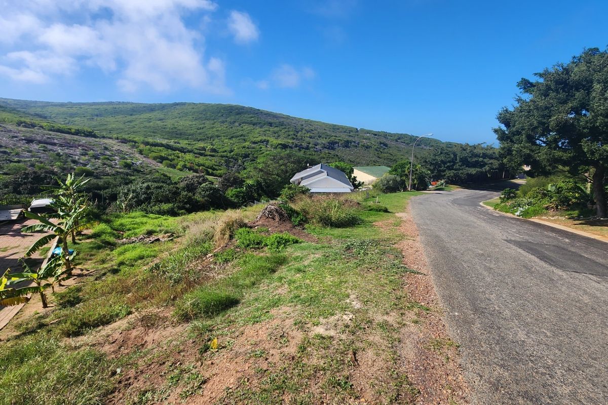 A view of the paved street and surrounding landscape, showcasing the residential plot's access and natural hillside setting.