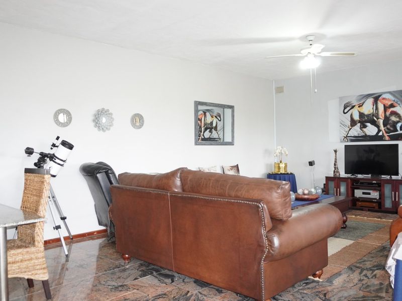 A spacious living room featuring polished stone tile flooring and a ceiling fan, offering a comfortable and functional layout for relaxation.