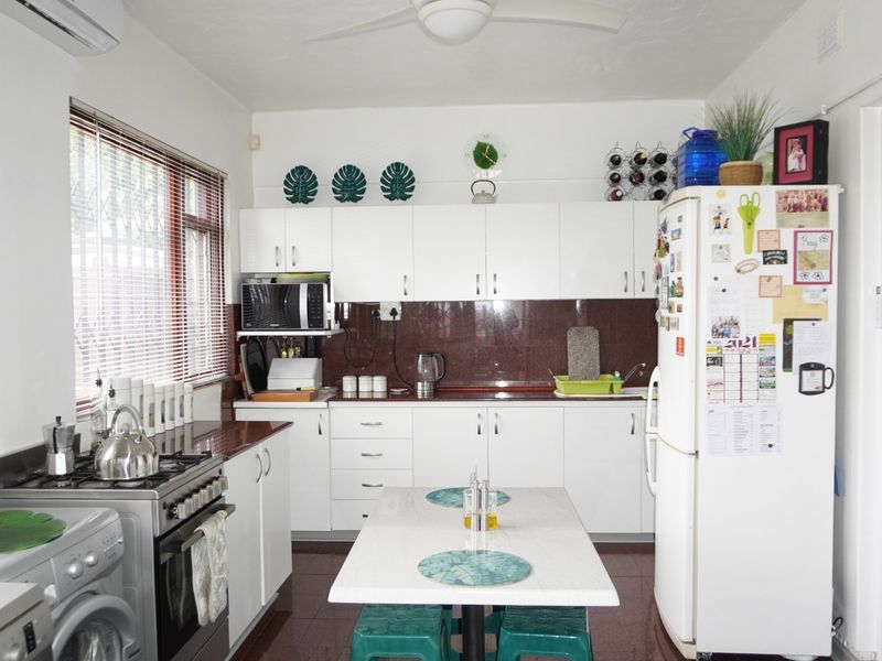 A functional kitchen featuring white cabinetry, a gas stove with oven, tiled splashback, and integrated appliances, offering a clean and practical workspace.