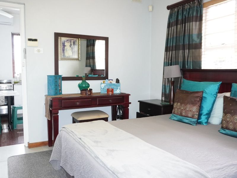 A bedroom featuring a ceiling fan and air conditioning unit, with an adjoining laundry area visible through the doorway.