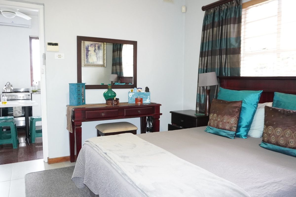 A bedroom featuring a ceiling fan and air conditioning unit, with an adjoining laundry area visible through the doorway.