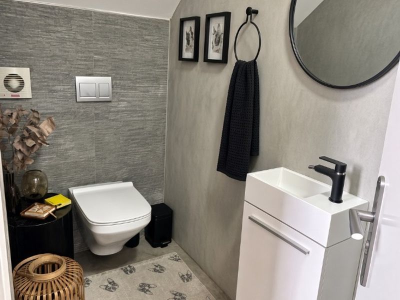 Modern guest bathroom featuring a wall-mounted toilet with concealed cistern, sleek vanity unit with basin, and contemporary grey tiled finishes.