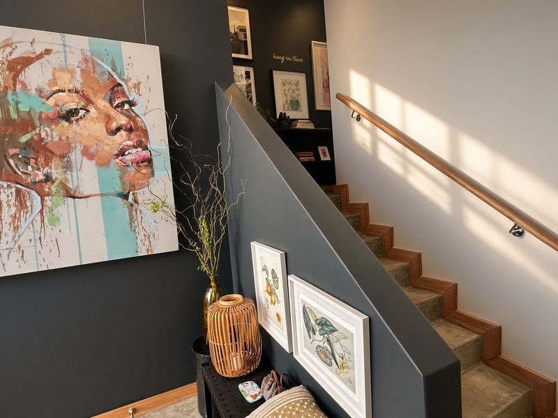 A modern entrance area featuring a staircase with a wooden handrail and a striking dark-painted feature wall.