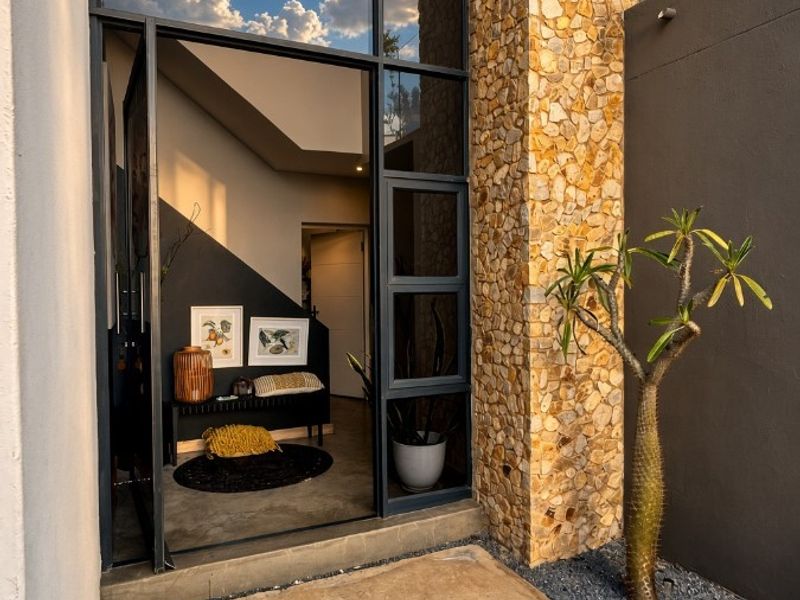 Modern entrance featuring striking stone cladding, a full-height glass door, and a concrete landing, creating a sophisticated and welcoming architectural facade.