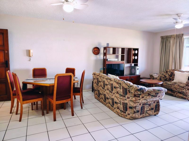 Open plan living and dining area featuring ceramic floor tiles and dual ceiling fans, offering a functional layout for daily living.