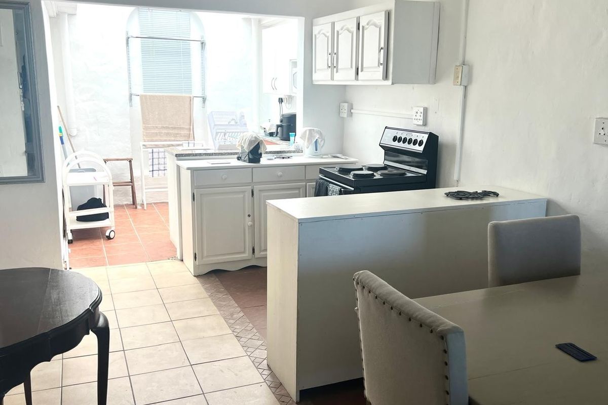 A functional kitchen area featuring tiled flooring, built-in cabinetry, and a breakfast counter, offering potential for modernization and aesthetic updates.