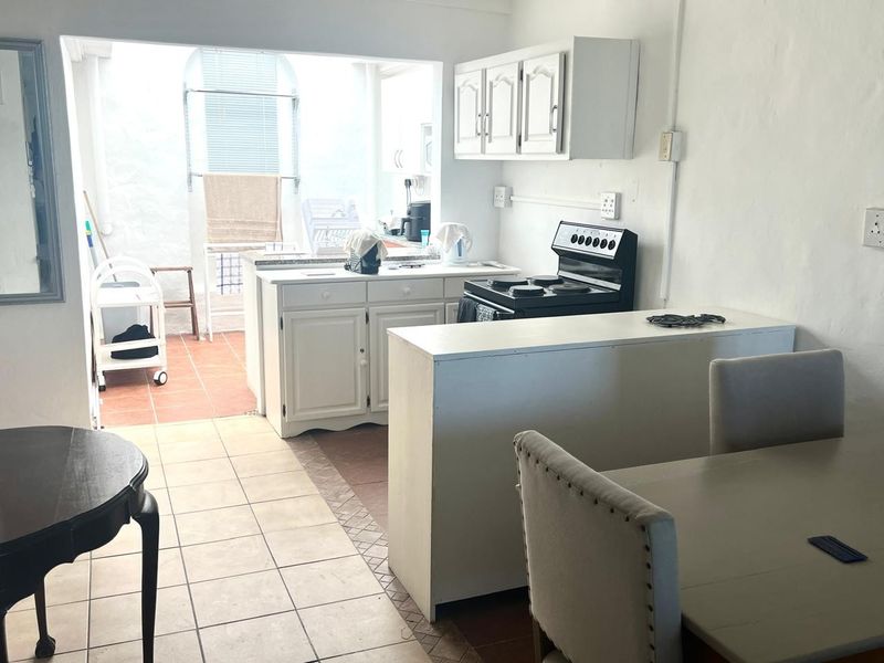 A functional kitchen area featuring tiled flooring, built-in cabinetry, and a breakfast counter, offering potential for modernization and aesthetic updates.