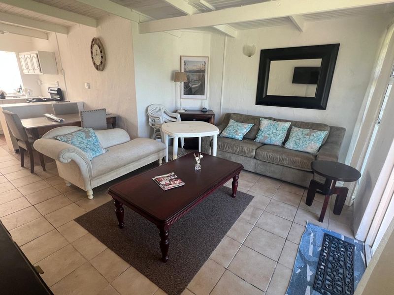 Open plan living and dining area featuring tiled flooring and exposed beam ceilings, seamlessly connected to a functional kitchen space.