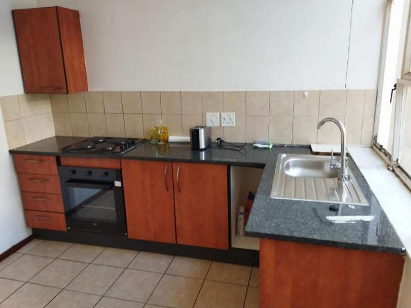 A functional kitchen featuring granite countertops, built-in oven, gas hob, and tiled finishes, offering a practical layout with potential for cosmetic updates.