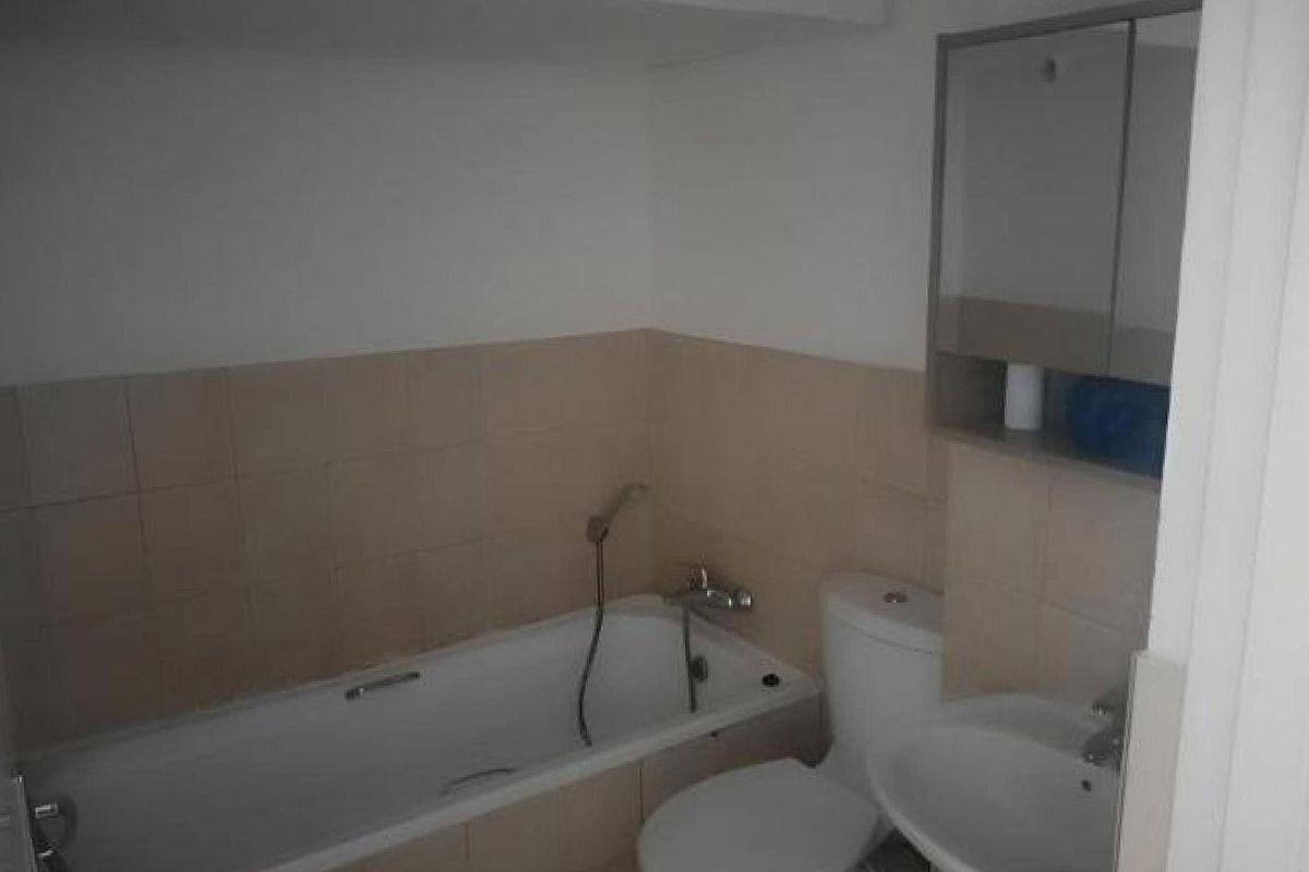 A functional bathroom featuring a bathtub with handheld shower, pedestal sink, toilet, and wall-mounted medicine cabinet with neutral tiled splashback.