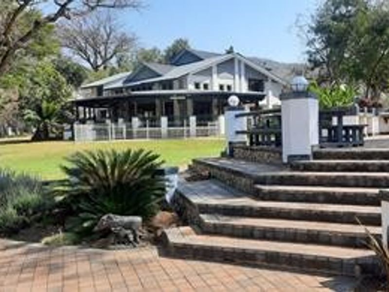 A spacious rear exterior view featuring a paved patio, stone staircase, and well-maintained garden leading to the main farmhouse structure.