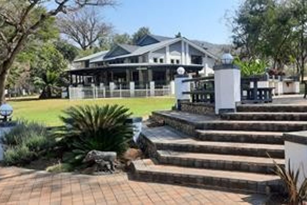 A spacious rear exterior view featuring a paved patio, stone staircase, and well-maintained garden leading to the main farmhouse structure.