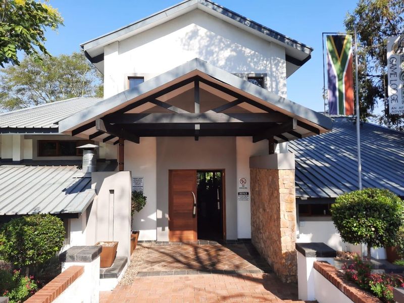 Front elevation of a farm-style lodge featuring a covered entrance porch, stone cladding accents, and a brick-paved walkway leading to a timber front door.