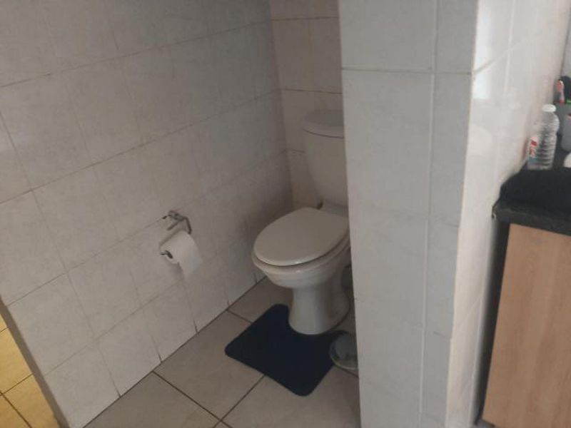 A functional bathroom space featuring tiled walls and flooring with a standard toilet installation.