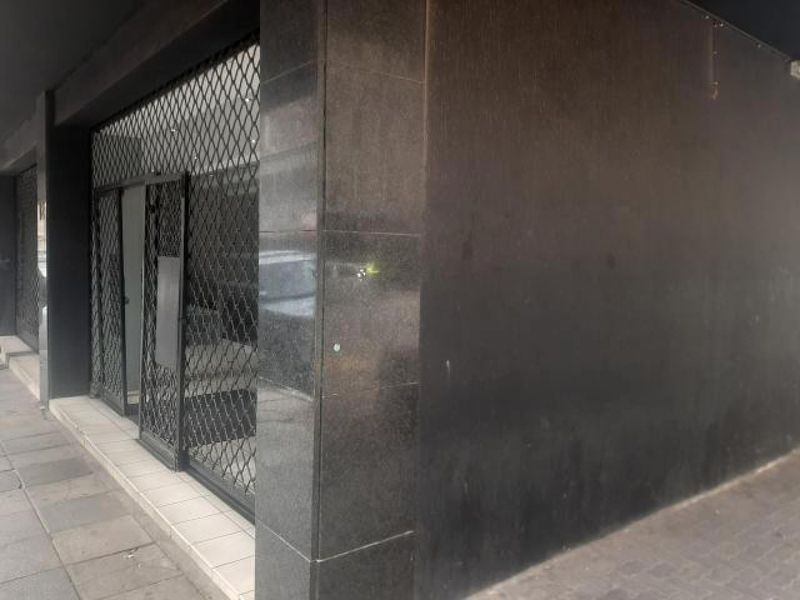 Exterior view of a commercial-style apartment entrance featuring dark granite cladding and a metal security gate.
