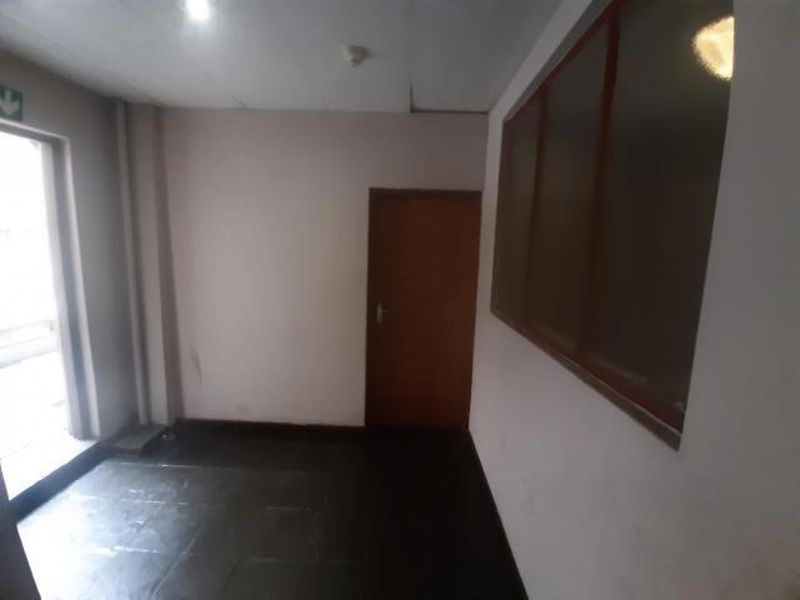 A vacant hallway featuring tiled flooring, an internal door, and a side window, presenting a blank canvas for potential interior updates.