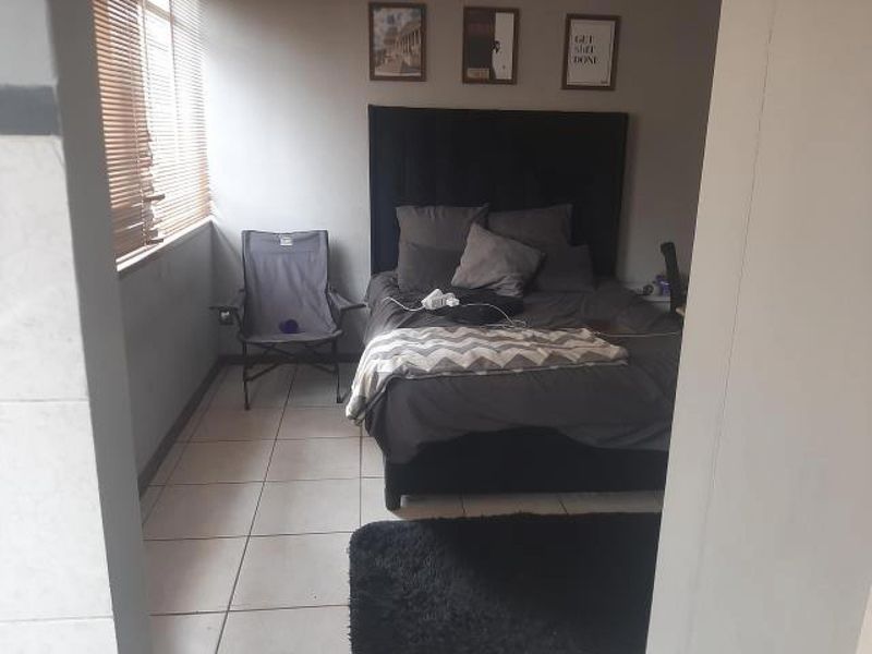 A bedroom featuring tiled flooring and venetian blinds, offering a functional space with neutral wall finishes.