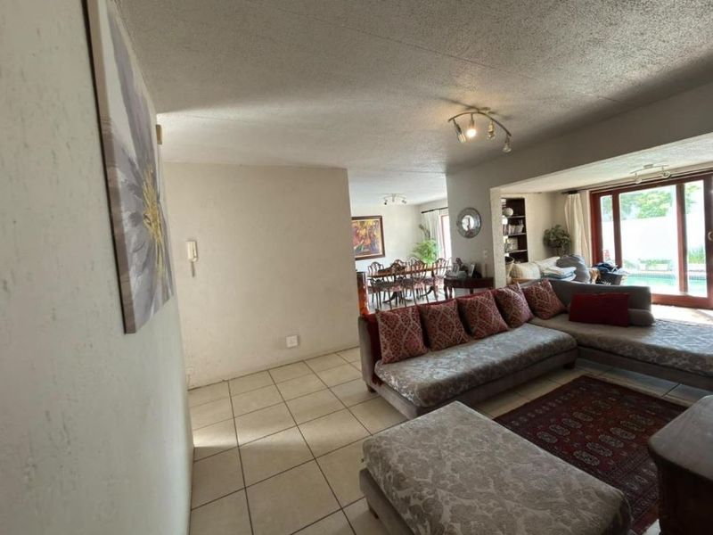 Spacious open-plan living and dining area featuring tiled flooring and large sliding glass doors that provide natural light and access to the outdoor pool area.