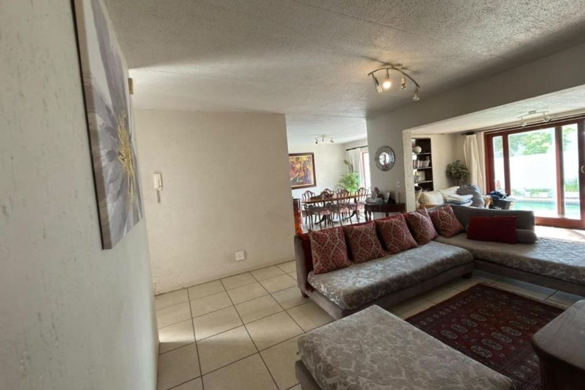 Spacious open-plan living and dining area featuring tiled flooring and large sliding glass doors that provide natural light and access to the outdoor pool area.
