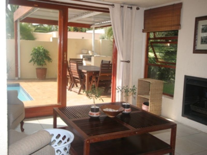 A living room featuring a built-in fireplace and large sliding glass doors that open onto a covered patio and pool area.