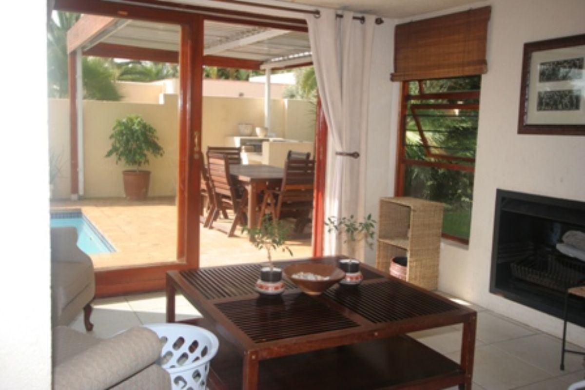 A living room featuring a built-in fireplace and large sliding glass doors that open onto a covered patio and pool area.
