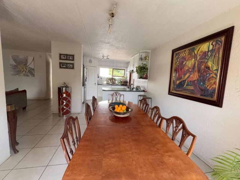 Open plan dining and kitchen area featuring tiled flooring and functional cabinetry, providing a connected living space.