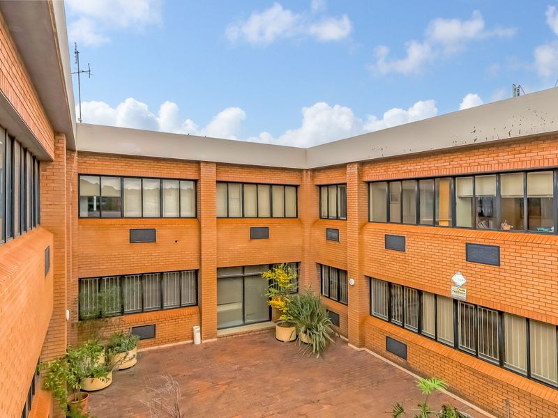 An elevated view of a brick office building courtyard featuring paved flooring and multiple window bays with aluminum frames.