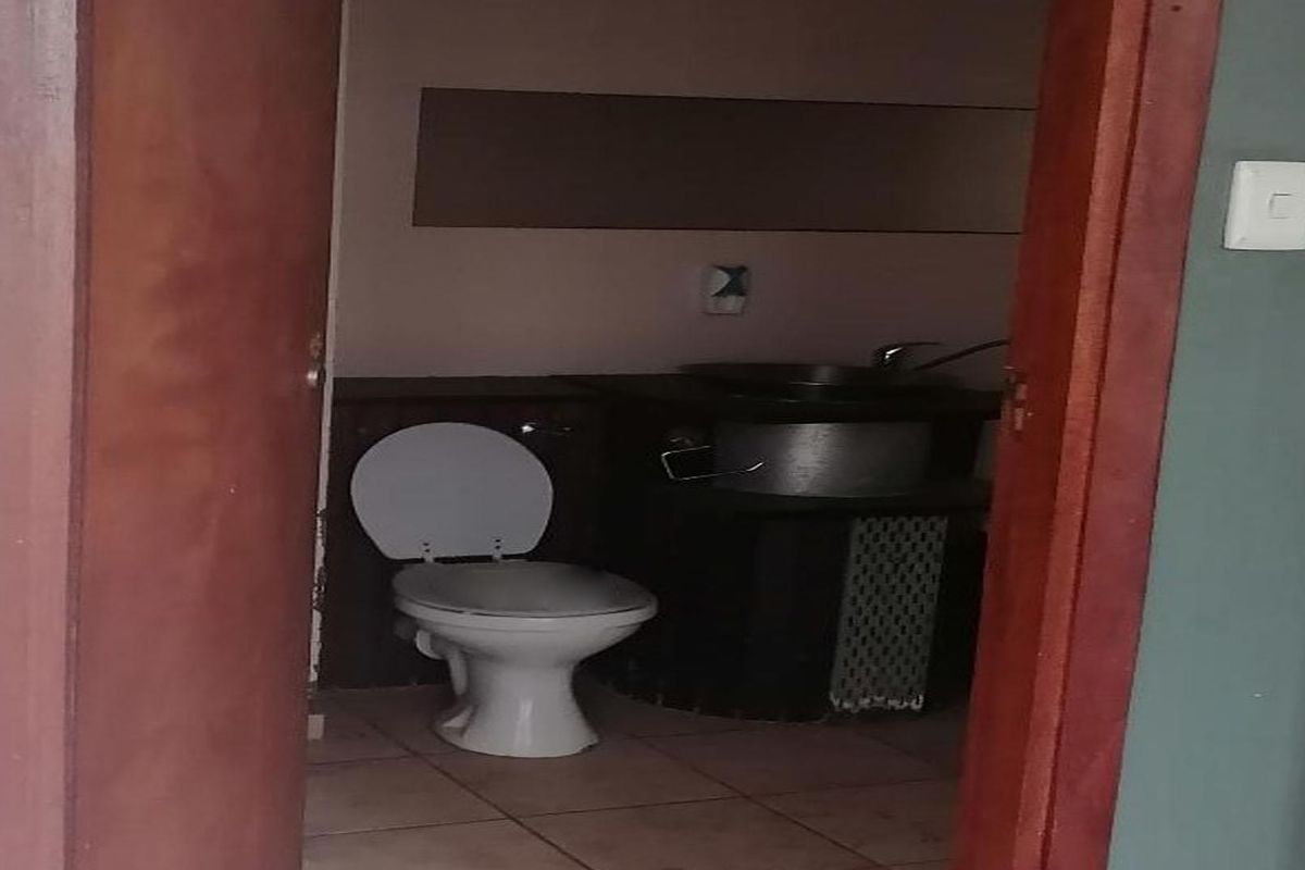 A compact bathroom featuring a standard toilet and a built-in washbasin area with tiled flooring.