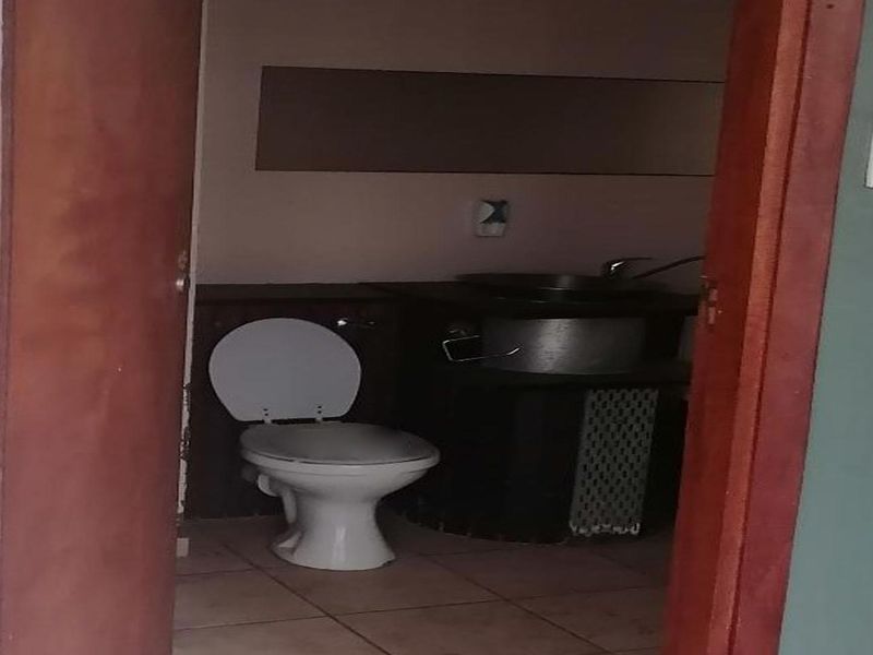 A compact bathroom featuring a standard toilet and a built-in washbasin area with tiled flooring.