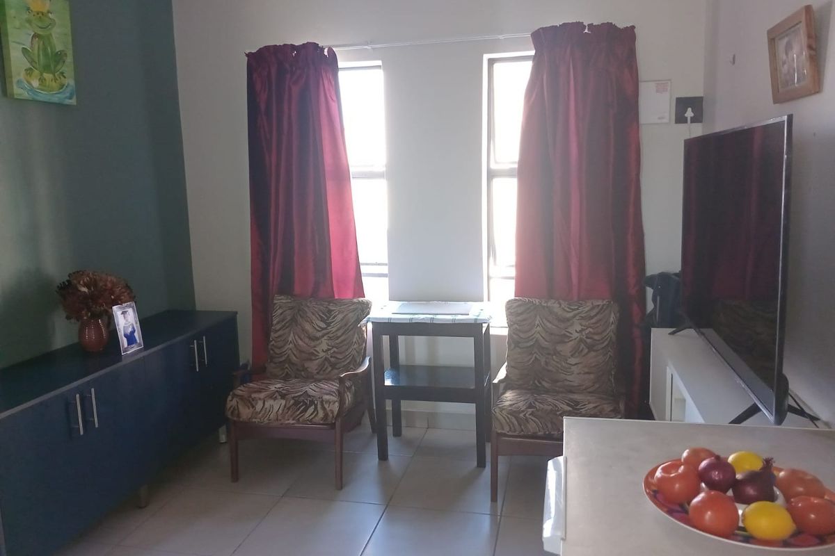 A functional living room area featuring tiled flooring and dual windows, providing a practical space for relaxation and daily living.