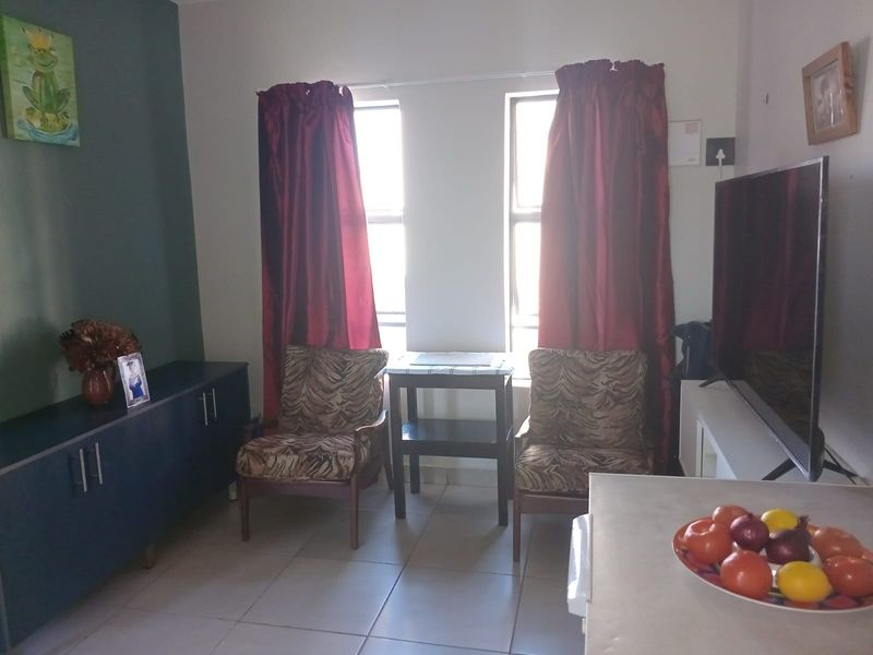 A functional living room area featuring tiled flooring and dual windows, providing a practical space for relaxation and daily living.