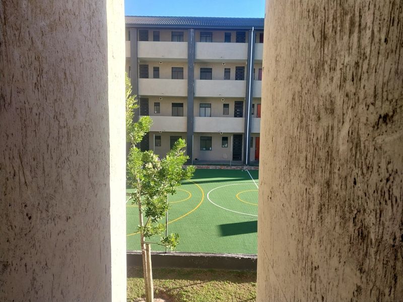 View of an apartment complex courtyard featuring a fenced sports court and multi-story residential building facade.