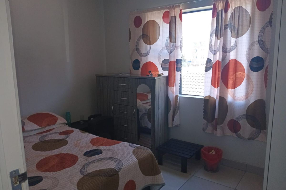 A functional bedroom featuring tiled flooring and a window, providing a neutral space ready for personalization.