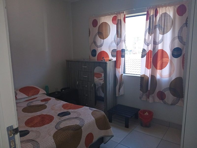 A functional bedroom featuring tiled flooring and a window, providing a neutral space ready for personalization.