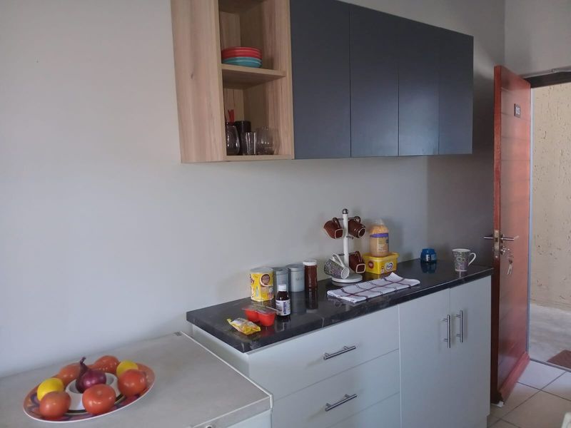 A compact kitchen area featuring modern two-tone cabinetry, dark stone-look countertops, and efficient drawer storage, providing a functional workspace.