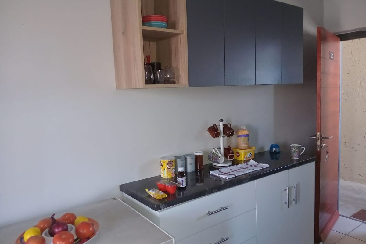 A compact kitchen area featuring modern two-tone cabinetry, dark stone-look countertops, and efficient drawer storage, providing a functional workspace.