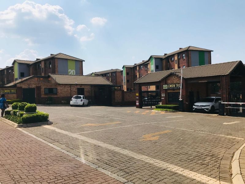 Front entrance and security access point of the Lemon Tree Apartments complex, featuring brick paving and established building facades.